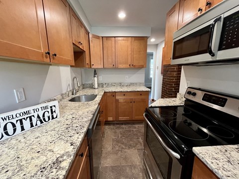 a cherry cabinet kitchen with granite counter tops and wooden cabinets